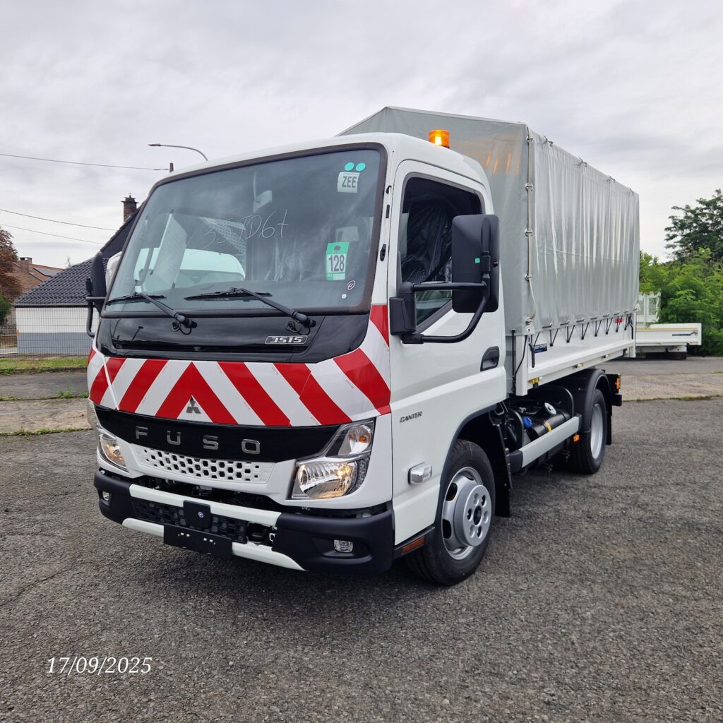 Fuso Canter benne bâchée – vue avant gauche avec chevrons et gyrophares.Fuso Canter benne bâchée – vue avant gauche avec chevrons et gyrophares.