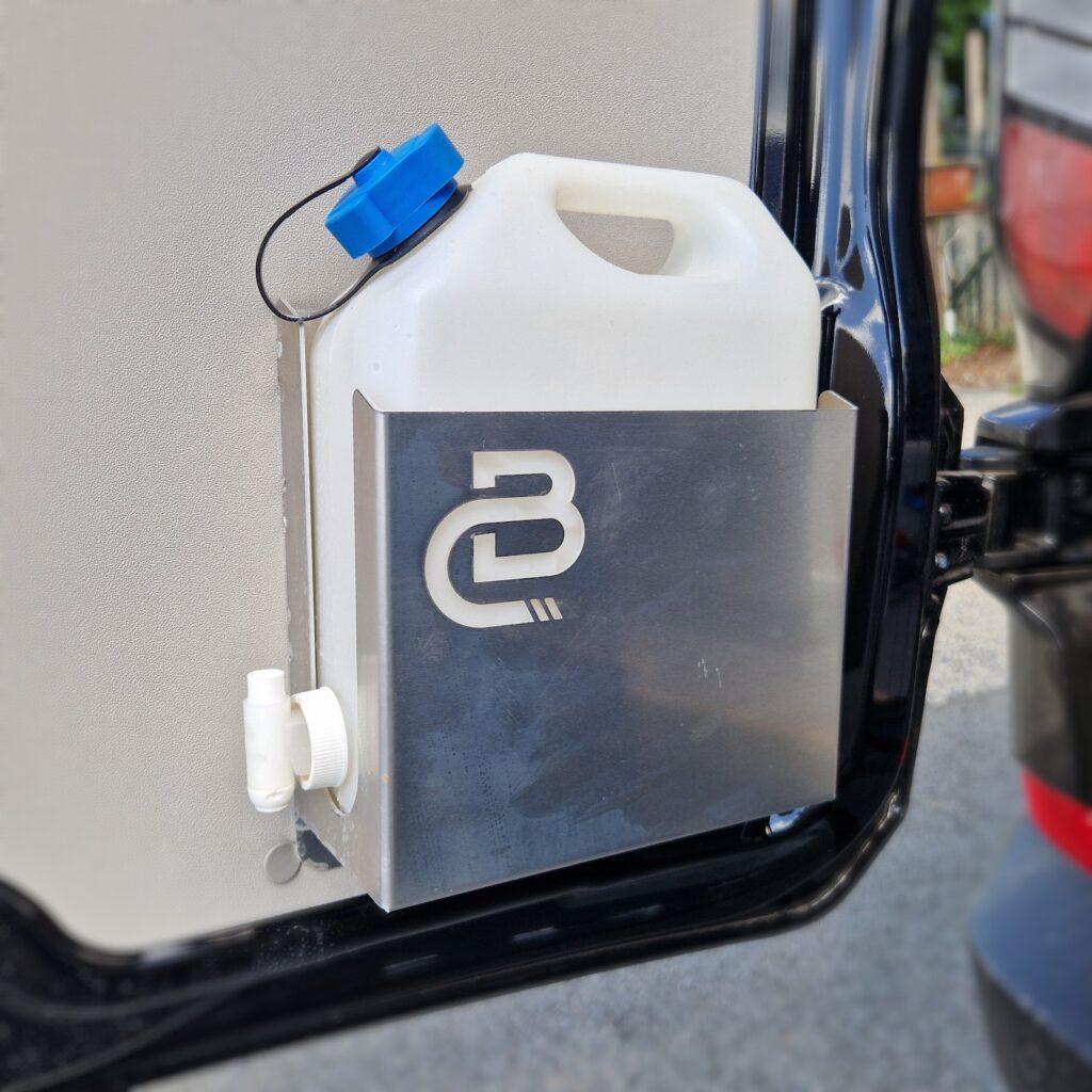 Support jerrycan fixé sur la porte arrière d’un utilitaire aménagé Body-Concept, avec bidon et robinet.
