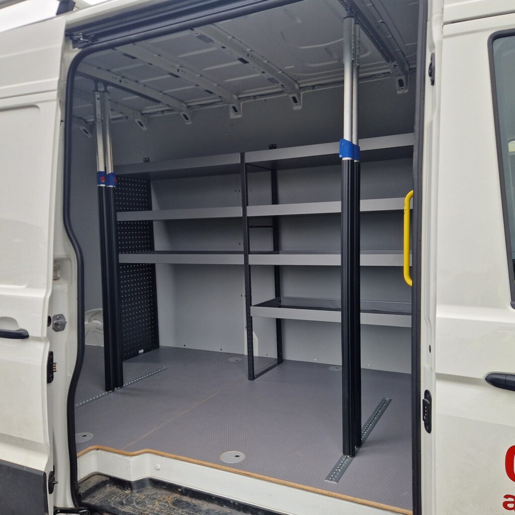 Intérieur d'un Volkswagen Crafter aménagé System Edström avec étagères métalliques, rangements modulaires et plancher antidérapant gris
