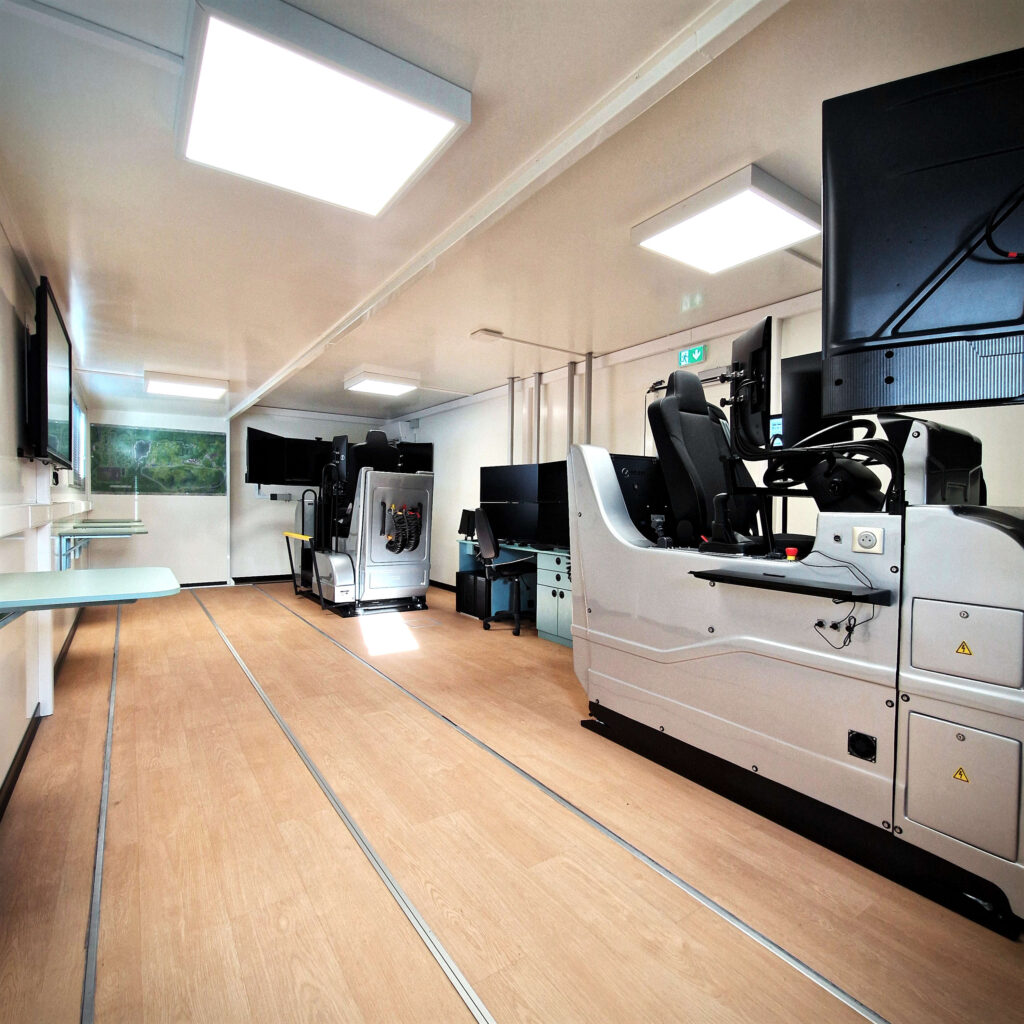 Intérieur du camion Le Forem : salle de cours avec deux simulateurs de conduite poids lourds et écrans